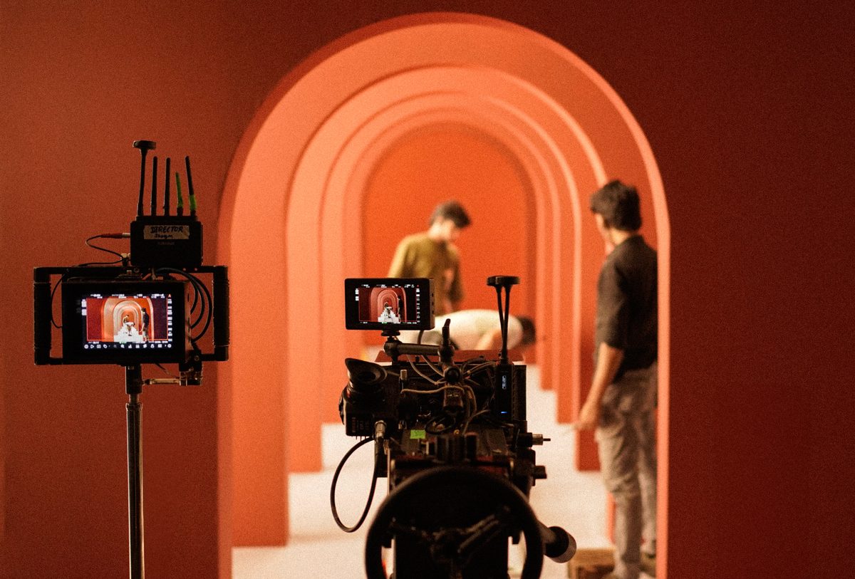 On set: camera monitors framing a beauty shot through a colonnade of arches
